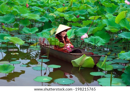 HANOI, VIETNAM, JUNE 07: Unidentified Vietnamese girl wear traditional costume on boat in lake of lotus on June 07, 2014 in Hanoi, Vietnam. Lotus blossom in June or July in VIetnam.