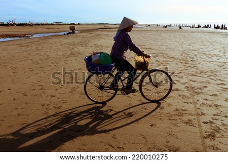 NAMDINH, VIETNAM - August 10 2014: Unidentified woman cycling in the marine fish trade in Namdinh, Vietnam. Buying and selling fish at the coast is traditional of Vietnamese fishermen.