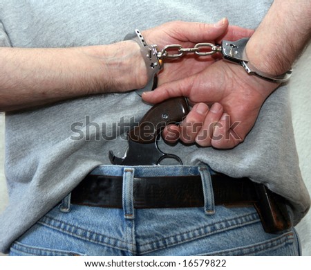 man in handcuffs pulls a gun from his back