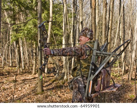 bow hunter in camouflage pulling back a compound bow in the forest