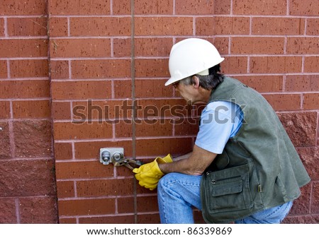 worker in hard hat and gloves uses wrench on a plumbing fitting