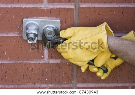 plumber repairing an outdoor water faucet on a brick wall