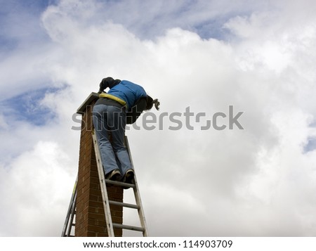 woman on a high extension ladder cleaning a brick chimney