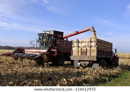 combine filling a farming truck with corn from a wisconsin crop harvest