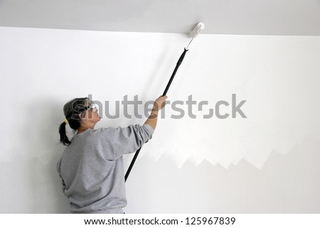 woman worker painting a ceiling with a roller