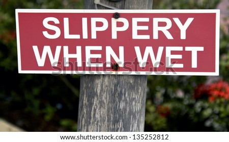 slippery when wet sign on a wooden post