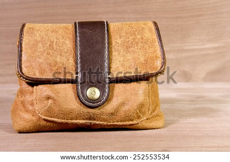 Retro suede leather satchel bag with a wooden background