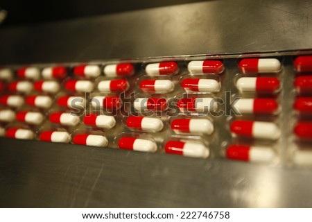 Red and white capsules pills drug production line, tablets coming out of the machine