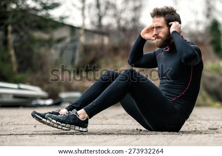 A shot of an athlete doing sit-ups outside