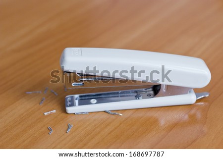 Stapler with the scattered paper clips on a desktop