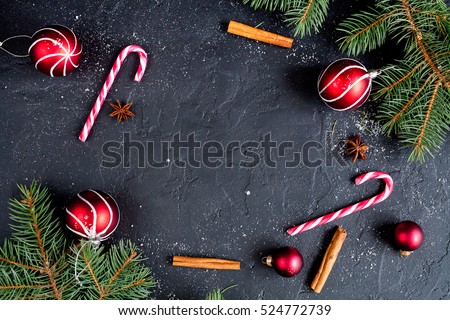 Christmas dark background with christmas decoration, christmas candy canes, fir branch, top view