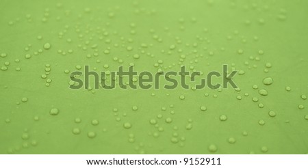 Water drops pattern on a green waterproof cloth
