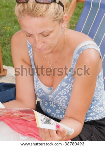 Beautiful blond woman sitting on the chair and  reading a magazine