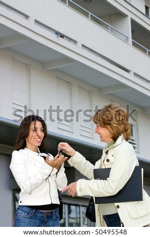 Real Estate woman Agent giving an apartment keys to young woman customer