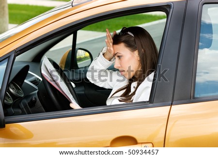 Despair young female driver sitting in the car and looking at a road map