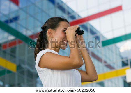 Smiling young business woman looking through binoculars.