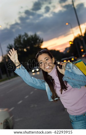 Portrait of lovely girl hailing a taxi in the street at night.