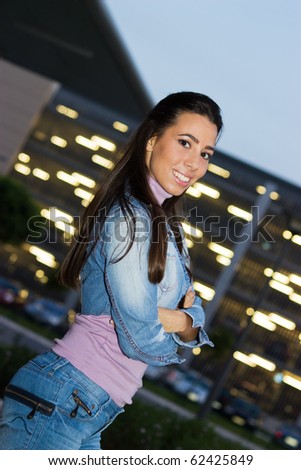 Lovely teenage girl posing in front of shopping mall in the night.