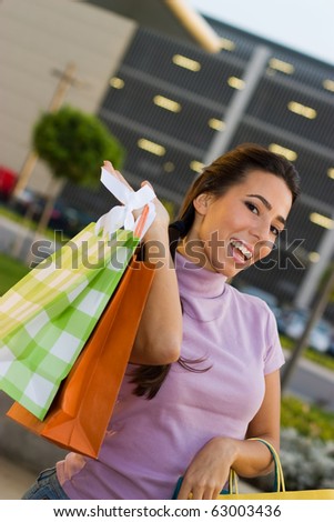Happy teenage  shopper standing  in front a shopping mall and holding a shopping bags.
