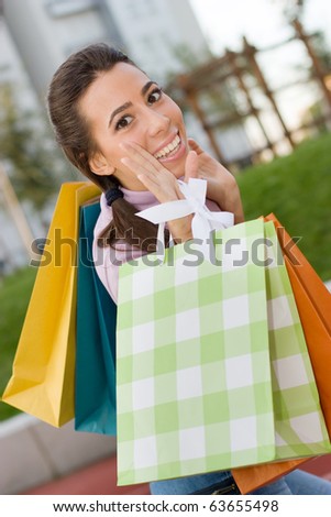 Lovely teenage girl holding shopping bags outdoors.