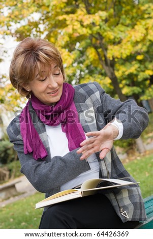 Charming mature businesswoman sitting on the bench and and checking the  time