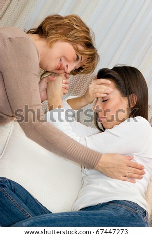 Mature mother consoling her young daughter in the living room.