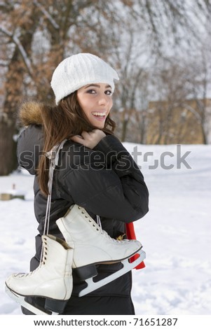 Beautiful young woman holding Ice Skate in her hand over shoulder outdoors on a sunny winter day.