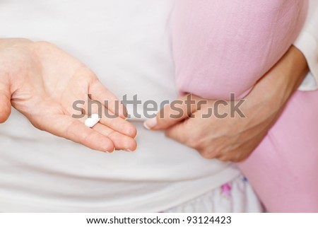 Close-up of female hands holding a pill in hand and pillow.