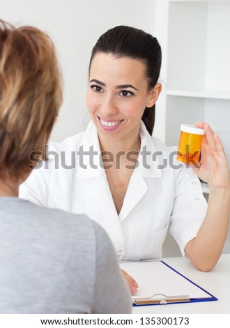 Friendly young female doctor sitting at the Doctor\'s Office with her mature patient and prescription Medicine.