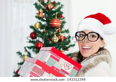 Young Woman in Santa hat with big black glasses holding  her Christmas gifts.