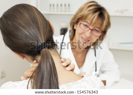 Young Woman Holding Her Neck And Talking With Female Doctor.