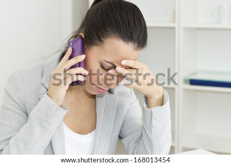 Businesswoman with hand on fer head talking by mobile.