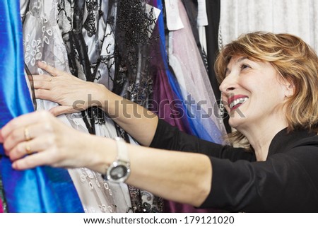 Happiness mature woman choosing a new dresses.