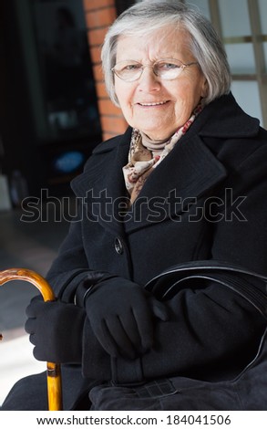 Portrait of smiling senior woman holding a walking stick looking at camera.