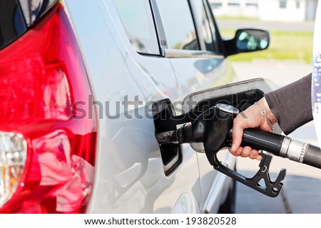 Closeup of woman hand pumping gasoline fuel in car at gas station.