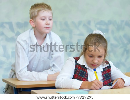 The boy tries to peep that the girl writes