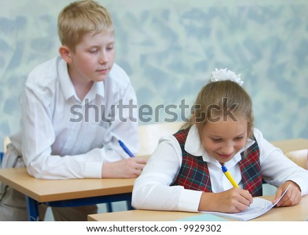 The boy tries to peep that the girl writes