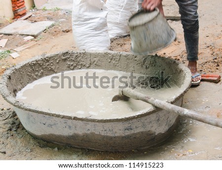 Construction worker mixing cement mortar plaster for interior walls