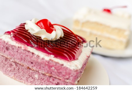 cake with mousse whipping cream and cherry on top. Shallow Depth of field with focus on the cherry