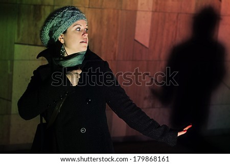 frightened young woman, male shadow in the background with a knife in his hand