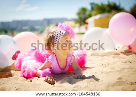 Portrait of beautiful little girl playing with air balloons at the beach