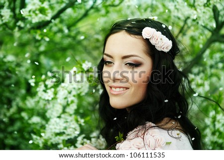 Beautiful young brunette woman standing near the apple tree