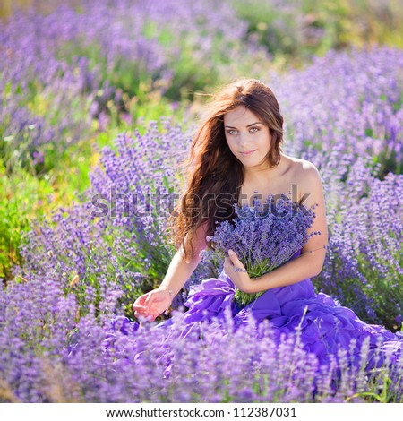 Portrait of beautiful romantic woman in fairy field of lavender with bouquet