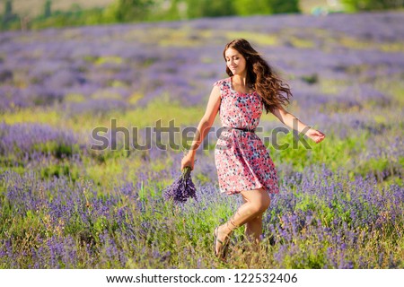 Carefree adorable girl with bouquet in fairy field of lavender. Summer freedom enjoy concept