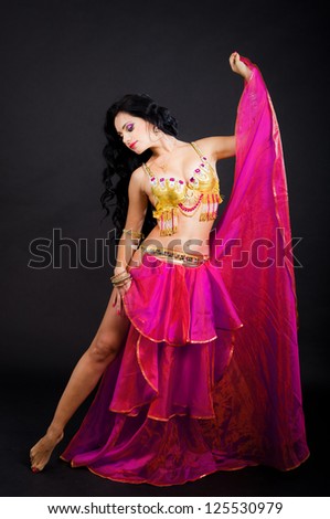Beautiful sexy woman belly dancer. Arabian oriental professional artist in shining costume with long healthy glossy hair