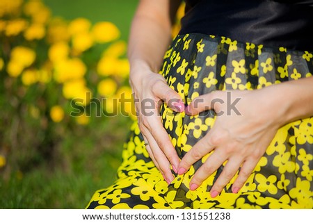 Pregnant woman holding hands on belly in shape of heart