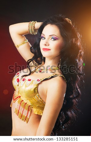 Beautiful sexy woman belly dancer. Arabian oriental professional artist in shining costume with long healthy glossy hair.