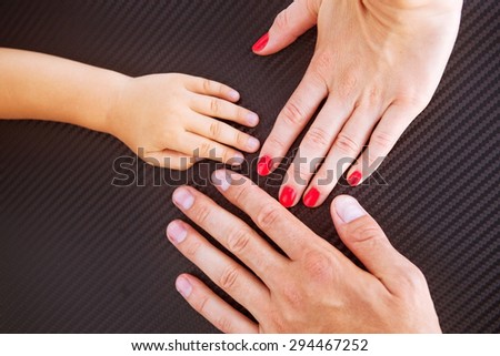 Three hands of the family- baby, mother and father. Concept of family, unity, protection, support and happiness.
