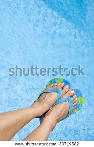 Woman\'s Feet Wearing Flip Flops Over a Swimming Pool