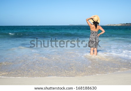 Back View of a Woman in Animal Print Sundress and Straw Hat Standing in the Ocean